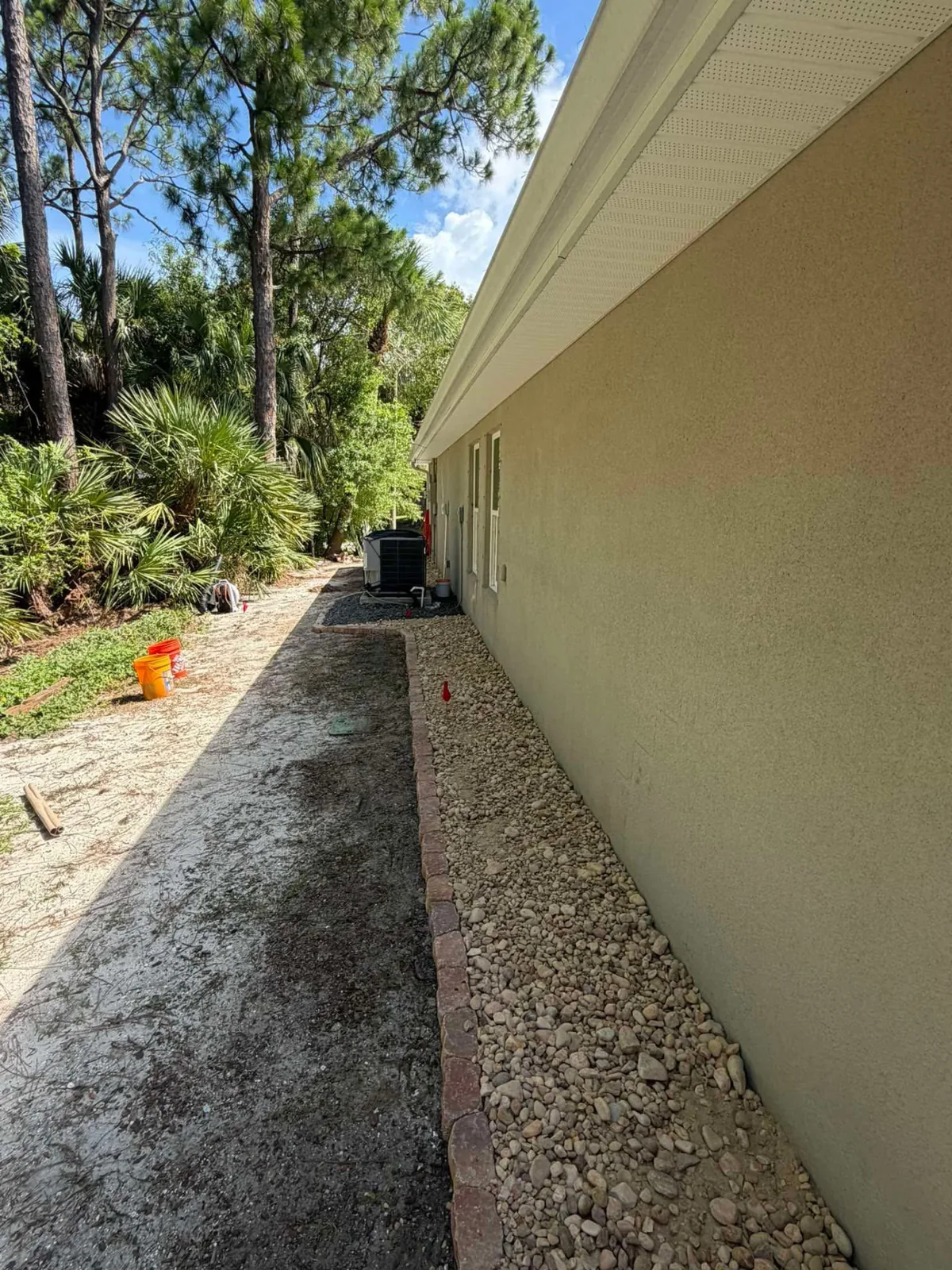 Decorative rock installation underway along the side of a home