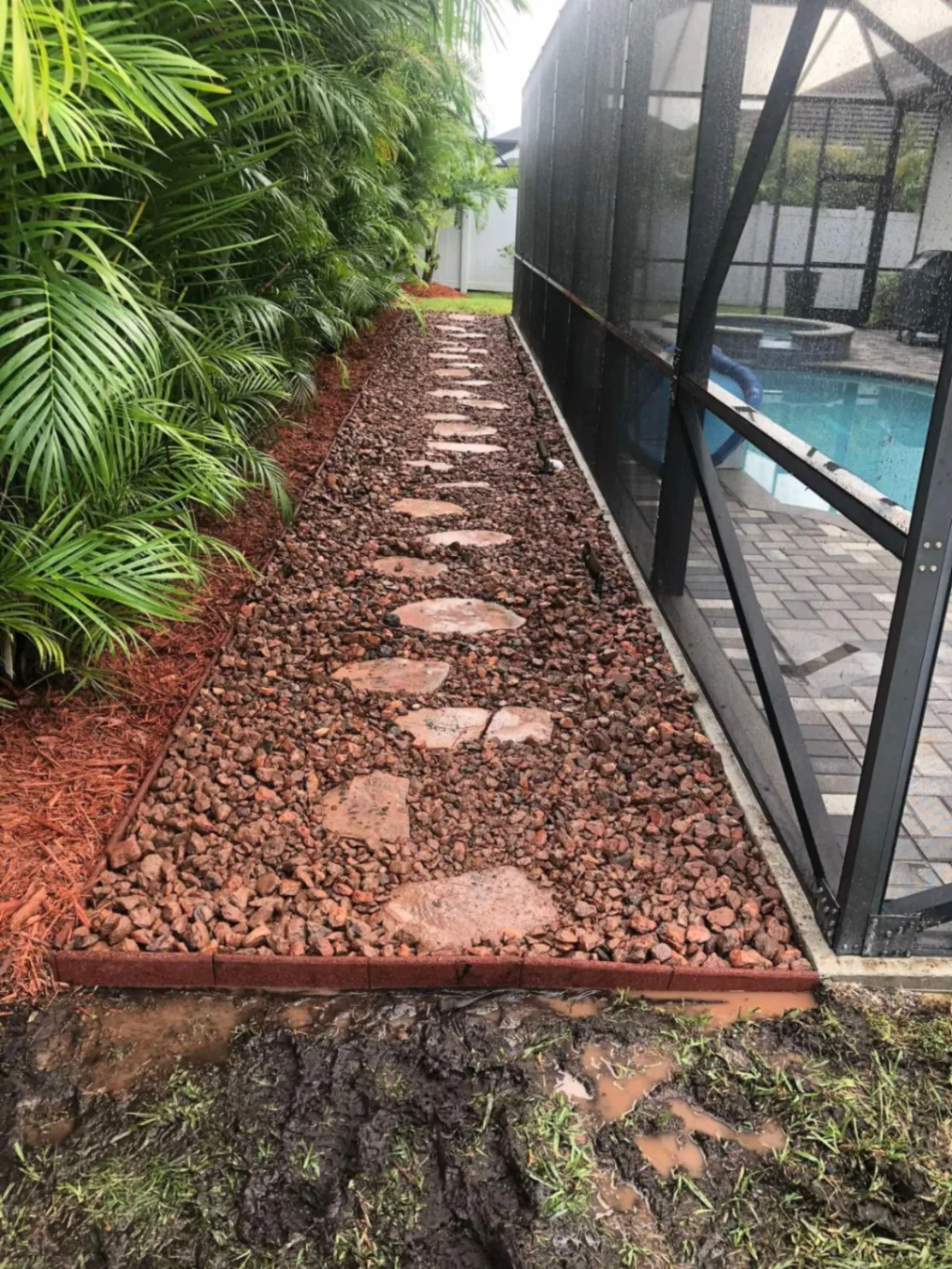 Red lava rock path with flagstone stepping stones beside a pool enclosure